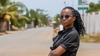 A young woman standing outdoors wearing a black button up shirt and sunglasses in Ghana 2024
