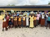 Louange Koffi in a group photo with a large group of people holding up some of her work products.