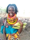 Lucia Epur Lebasha smiling in a brightly coloured outfit smiling and holding some fresh corn