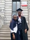 Ipti at her graduation smiling to camera with a friend 