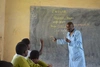 Man stood teaching with a blackboard in the background 