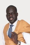 Headshot of Bior Ajak, wearing a yellow suit with a striped blue and white tie