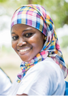 A young woman wearing a headscarf and smiling at the camera.