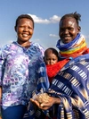 Grace Aipa outdoors with a pastoral woman farmer and child