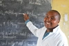 Man smiles to camera writing on blackboard