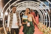 Two young people walking down a red carpet dressed in formal dress wear