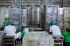 Two people in white jumpsuits working in a food manufacturing facility