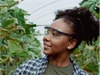 A young female farmer inspecting the crops on a vibrant agricultural landscape.