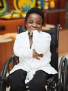 Stephanie Egharevba in her wheelchair in a long sleeved white button up shirt.