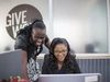 Two women looking at a laptop screen and smiling.