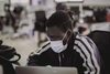 Young man sitting at a desk in front of a laptop wearing a protective face mask