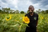 Gordon Victor smiling in a field of sunflowers in Uganda