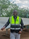 Vasco Hamisi standing in front of one of his large solar panels that provides electricity to Kakuma refugee camp, Kakuma, Kenya, 2025
