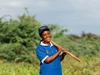 Irene Nimbona smiling outside in a dark blue ball cap and a bright blue t-shirt with a white collar