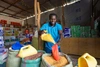 Man in a blue shirt pouring corn into a grocery bag for sale.