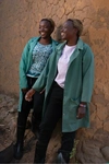 Two young women standing outdoors wearing dark green work coats for Practical Action, Kenya, 2024