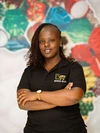 Christine Ng’ang’a, Co-founder of Soko Kijiji posing for a portrait shot and wearing a black gold t-shirt branded with the Soko Kijiji logo.