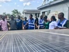 Vasco Hamisi co-founder of Okapi Green, wearing a blue vest and speaking to a group of people over a large solar panel