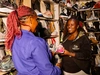 Christine Ng’ang’a, Co-founder of Soko Kijiji with a shoe vendor at her stall speaking together.