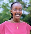 Joyce Mahoro smiling in a pink top with a gold necklace.