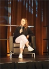 A seated woman speaking into a microphone.