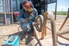Mariam Sulaiman smiling and wearing her protective welding gear, in Kakuma refugee camp, Kenya, 2026