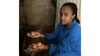 Woman crouching with eggs in each of her hands