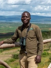 A man standing at a fence with a beautiful view behind him.