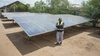 Vasco Hamisi standing in front of his large solar panels, Kakuma refugee camp, 2025