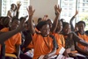 Students raising their hands in a classroom.