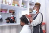 A woman in a face mask blow-drying someone's hair.