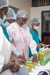 Armande Lo, a young entrepreneur in the Suqali Program in WAEMU, stood with others in a row inspecting drink bottles on a table in front them