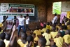 Group of students sat listening to a man speaking at the front of a classroom 