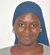 Marie Emilie Tine wearing a grey top, dark blue head wrap and gold earrings