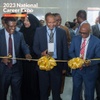 Three men stood in a line in smart suits holding scissors and cutting and ribbon and bow