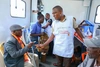 Man with a Saving Lives and Livelihoods apron on talks to other around him 