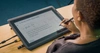 Person writing on a tablet on a desk