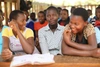 Three students smiling in a classroom.