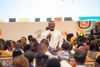A young man speaking on a microphone to a large room full of people at Day 1 of the Baobab Summit 2025