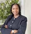 Ange Kalitanyi smiling in a smart black business top with gold buttons