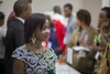 A young woman standing in a black and white patterned dress, among a group of people at a networking event.