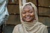 Pang Ismail, wearing a beige head scarf and smiling brightly, in Kakuma refugee camp, 2026.