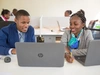 Two young professionals sitting at a desk and working on laptops together, African Management Initiative 2017