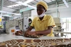 Worker in a yellow uniform sewing sat in front of a sewing machine 