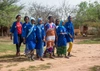 A group of women in blue coats walking, with trees in the background