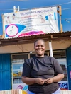 Victoria, standing outside and smiling, in front of her healthcare clinic, in Gurei, South Sudan 2026.