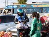 A young woman vegetable vendor, selling her goods to a vendor on a motorcycle, 4 x 3