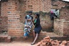 Two women sat on a wall looking at a mobile phone together 