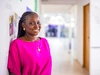 A woman standing in a hallway smiling in a brightly coloured pink top, Jobberman, Nigeria, 2024.