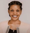 Sandrine Irankunda smiling in a beige cardigan, lined with a black pattern and a black shirt underneath